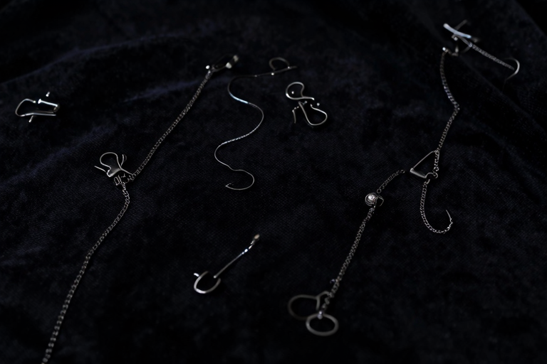 吸引グッズと乳首クリップが並べられたSM用品のイメージ、ダーク背景